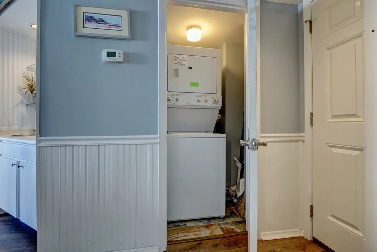 A compact, pristine laundry area with modern washer and dryer units, white cabinetry for storage, and framed wall art. The design ensures practicality without sacrificing style.