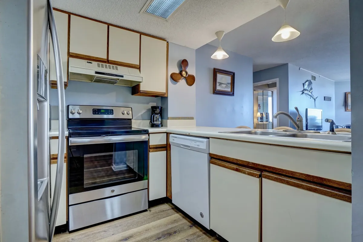 A modern kitchen with stainless steel appliances, a central island for meal prep or casual dining, and stylish wall art. This space is bright and functional, perfect for cooking or enjoying snacks with loved ones.